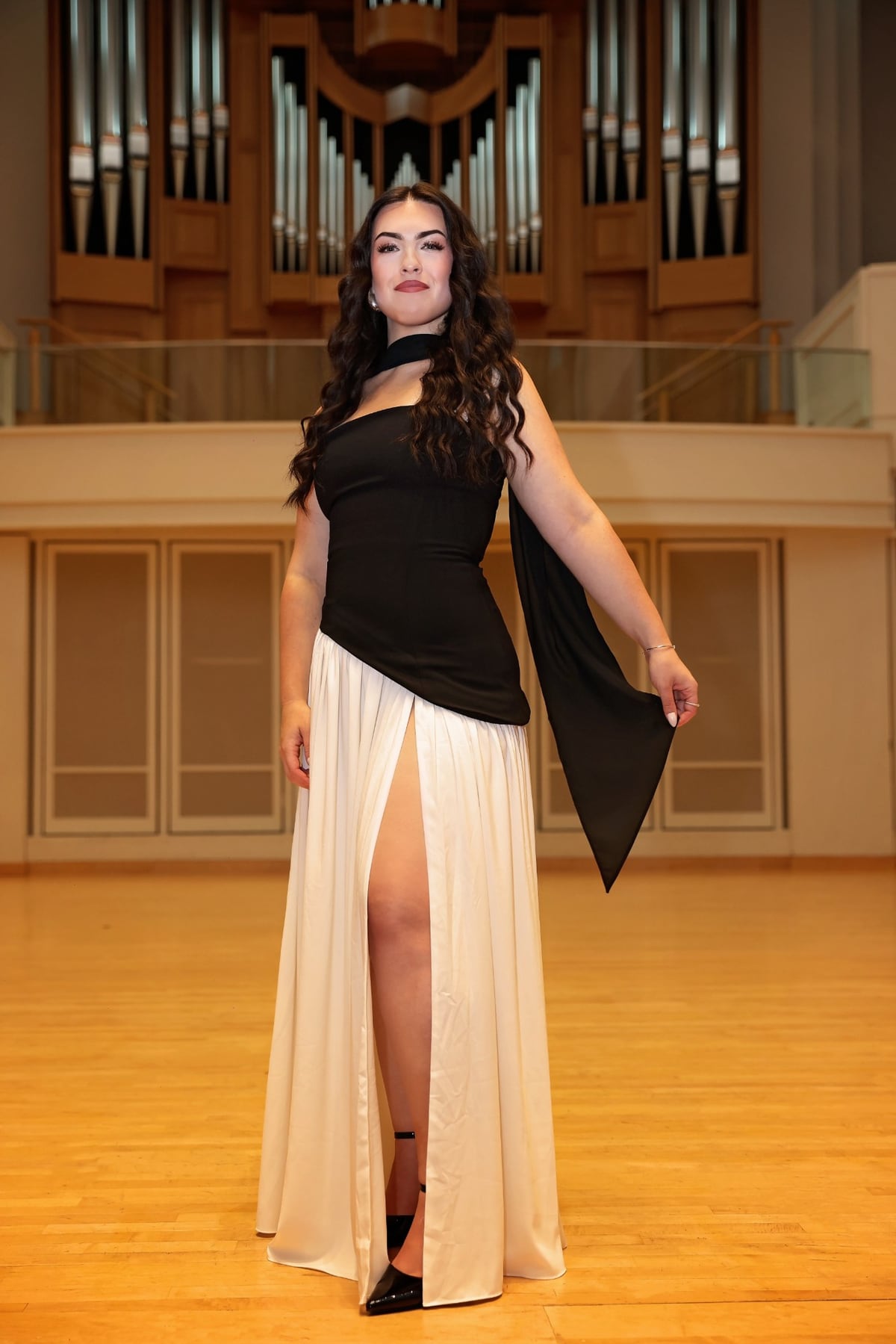Dana in a black-and-cream gown on a concert stage in front of a grand pipe organ