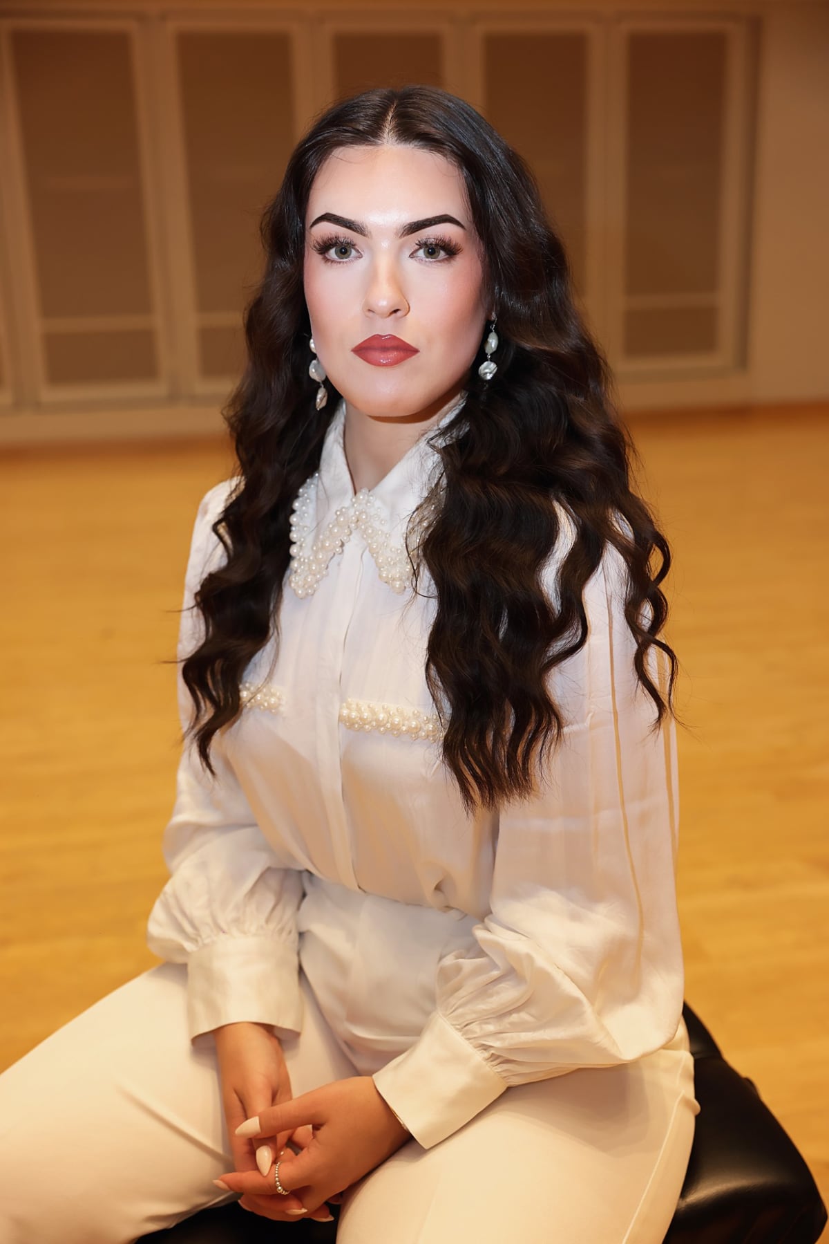 Dana seated in a recital hall wearing a pearl-collar blouse
