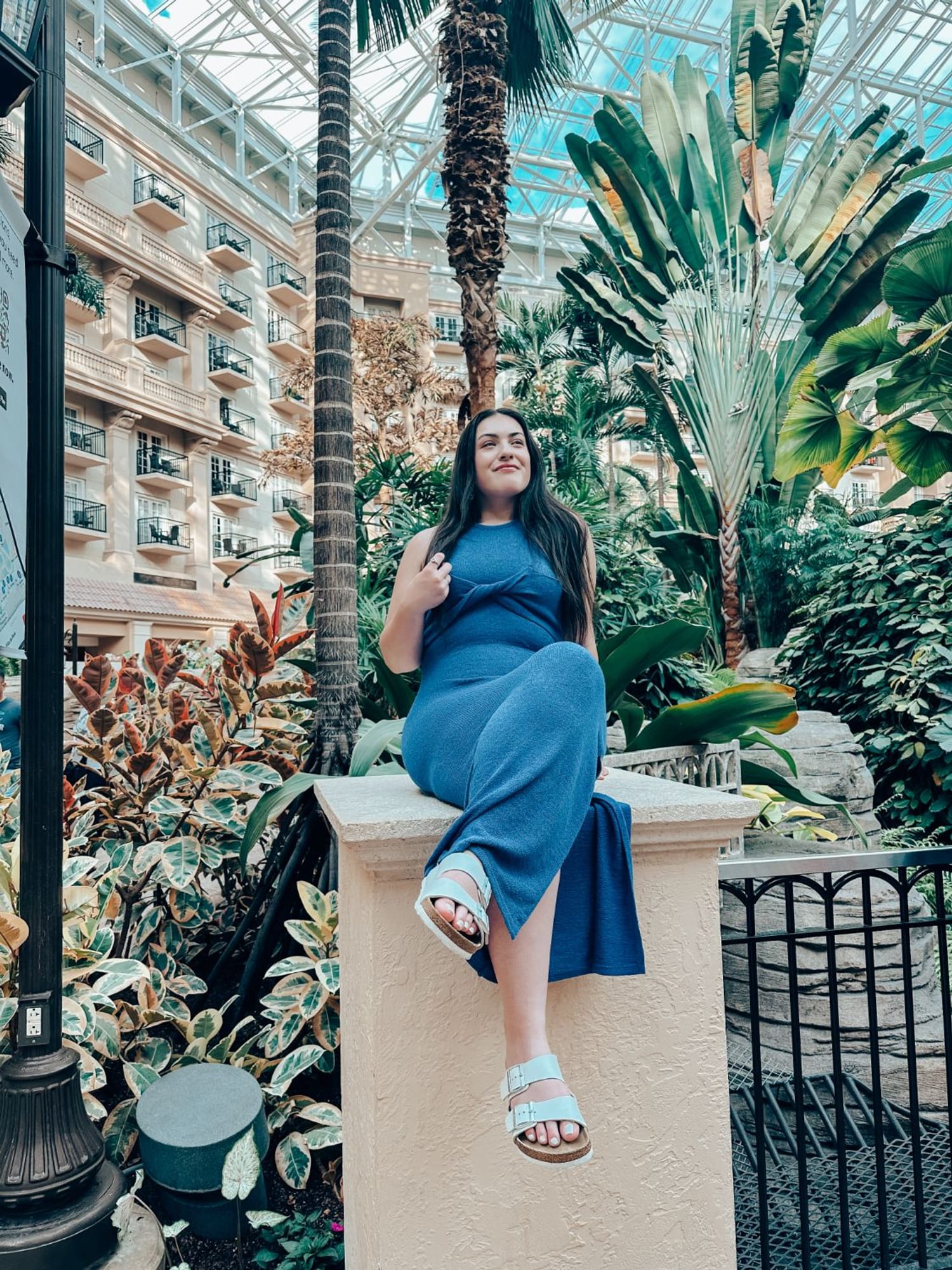 Dana seated in a light-filled tropical atrium