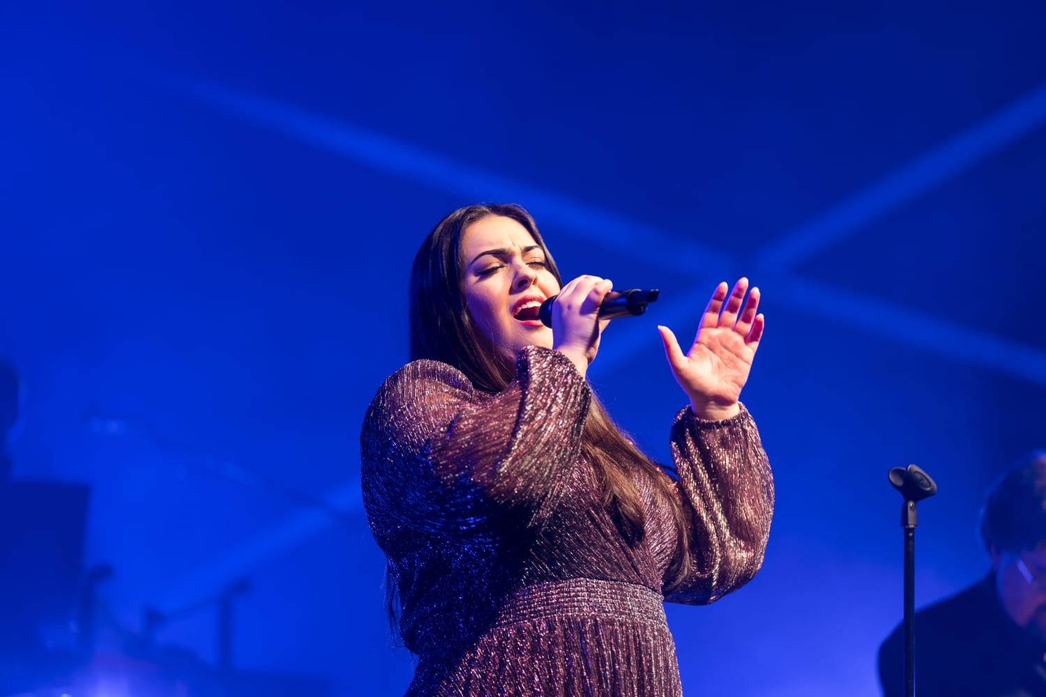 Dana singing under blue stage light